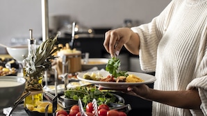 Un bufé con diferentes alimentos y una persona sirviéndose.