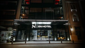 Exterior del EN HOTEL con fachada moderna, amplias ventanas de vidrio y una entrada destacada.
