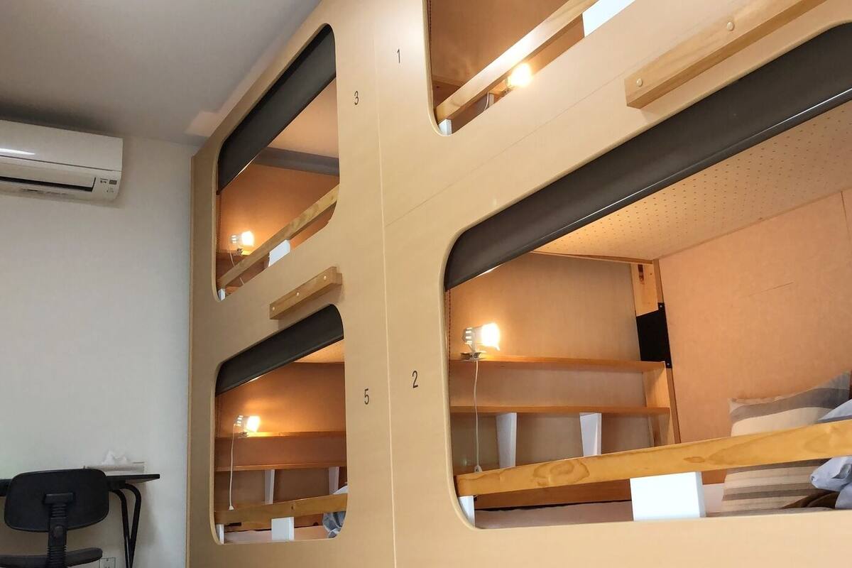 Una habitación tipo dormitorio con literas, un escritorio y un equipo de aire acondicionado.