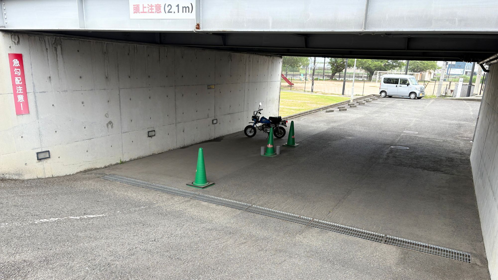 A parking area under a bridge with a motorcycle and traffic cones.