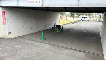 A parking area under a bridge with a motorcycle and traffic cones.