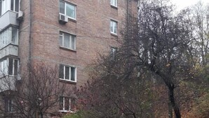 A multi-story brick building with a paved pathway and leaf-covered ground. - Home-Hotel Mechnikova 7 (Kyiv)