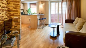 A modern living room with a stone accent wall, a coffee table, a sofa, and a kitchen area with a bar. - Home-Hotel Mechnikova 7 (Kyiv)