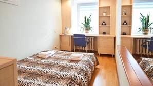 A bedroom with a bed, desk, chair, and two potted plants. - Home-Hotel Mechnikova 7 (Kyiv)