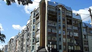 Un immeuble à plusieurs étages, doté de balcons, de grandes fenêtres et d’une entrée située à l’angle.