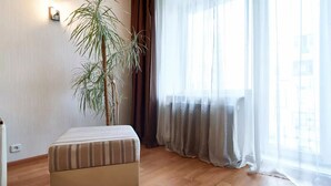 A room with a striped sofa, a tall plant, and sheer curtains. - Home-Hotel Nizhniy Val 41-2 (Kyiv)