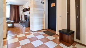 A hotel lobby with a checkered floor, a reception desk, a TV, and a door with a sign. - Home-Hotel Nizhniy Val 41-2 (Kyiv)