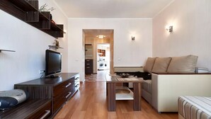 A modern living room with a flat-screen TV, wooden furniture, a sofa, and a dining table. - Home-Hotel Nizhniy Val 41-2 (Kyiv)