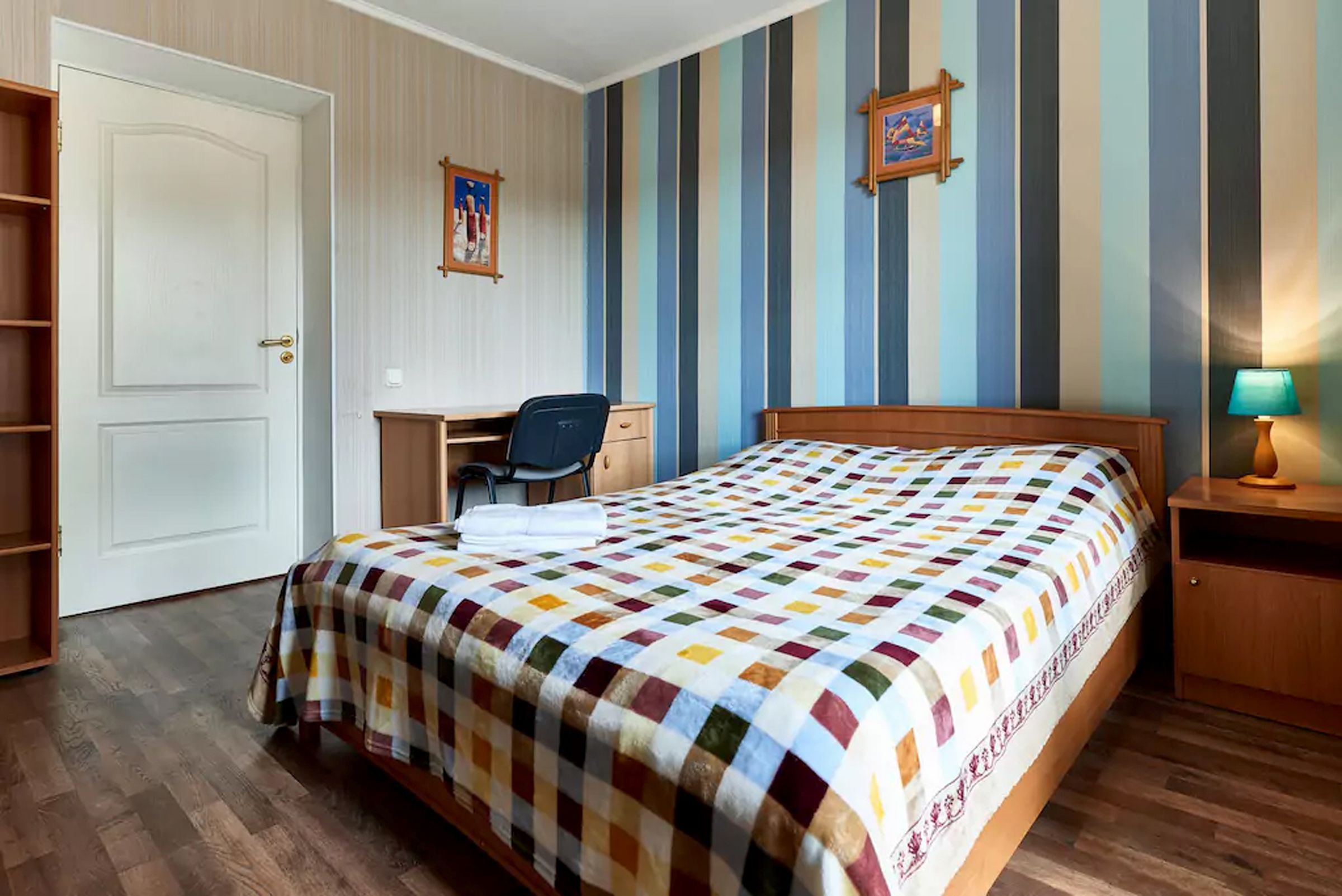 Une chambre à coucher comprenant un lit, un bureau, une chaise et une table de chevet avec une lampe.