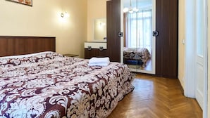 Een slaapkamer met een groot bed, een dressoir, een spiegel en een schuifdeur naar een balkon.