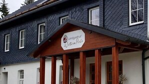 A building with a sign reading "Landgasthof Weterperle" and a dog walking in front. - Landgasthof Wetteraperle (Saalburg-Ebersdorf)