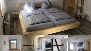 A modern bedroom with a wooden bed, a built-in bench, a TV, and a large window. - Landgasthof Wetteraperle (Saalburg-Ebersdorf)