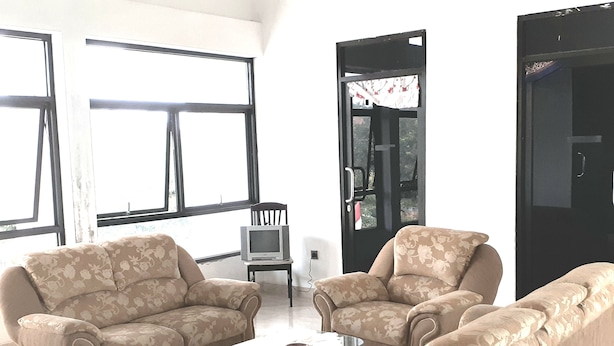 A living room with two sofas, a coffee table, and a television on a small table. - Almira Homestay (Jambi)
