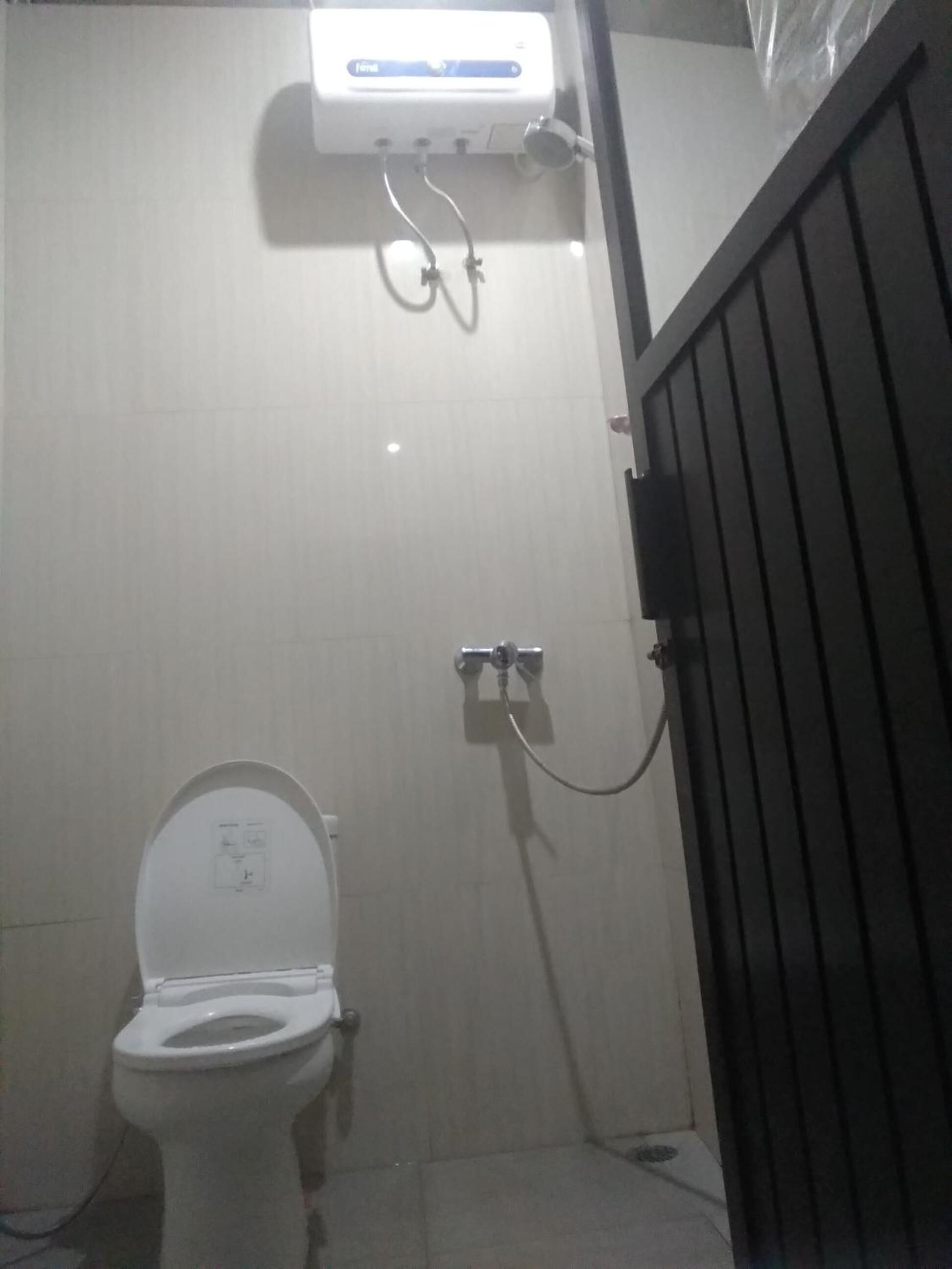 Un baño con inodoro, ducha y calentador de agua.