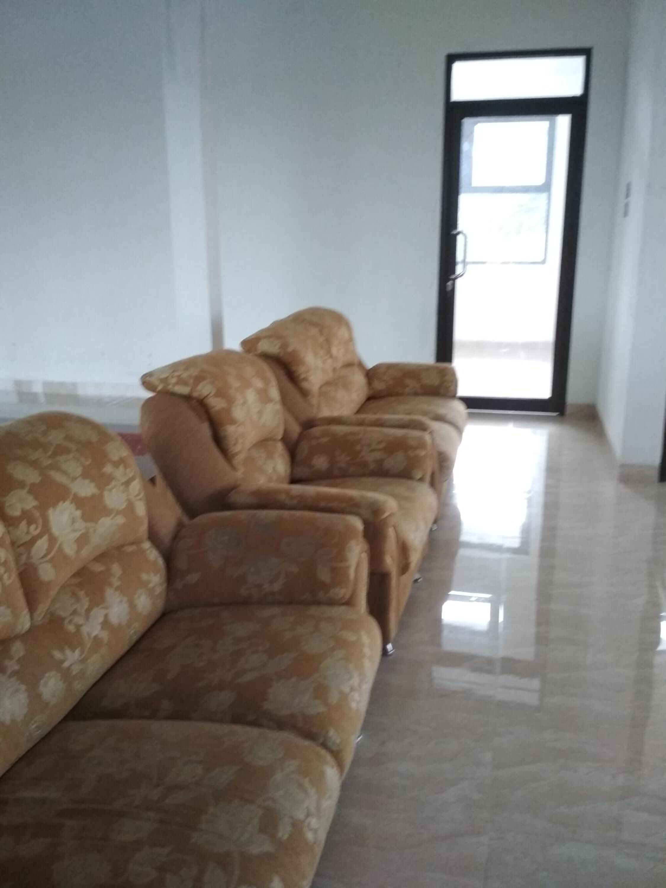 A living room with a sofa set and a door leading to an outdoor area.