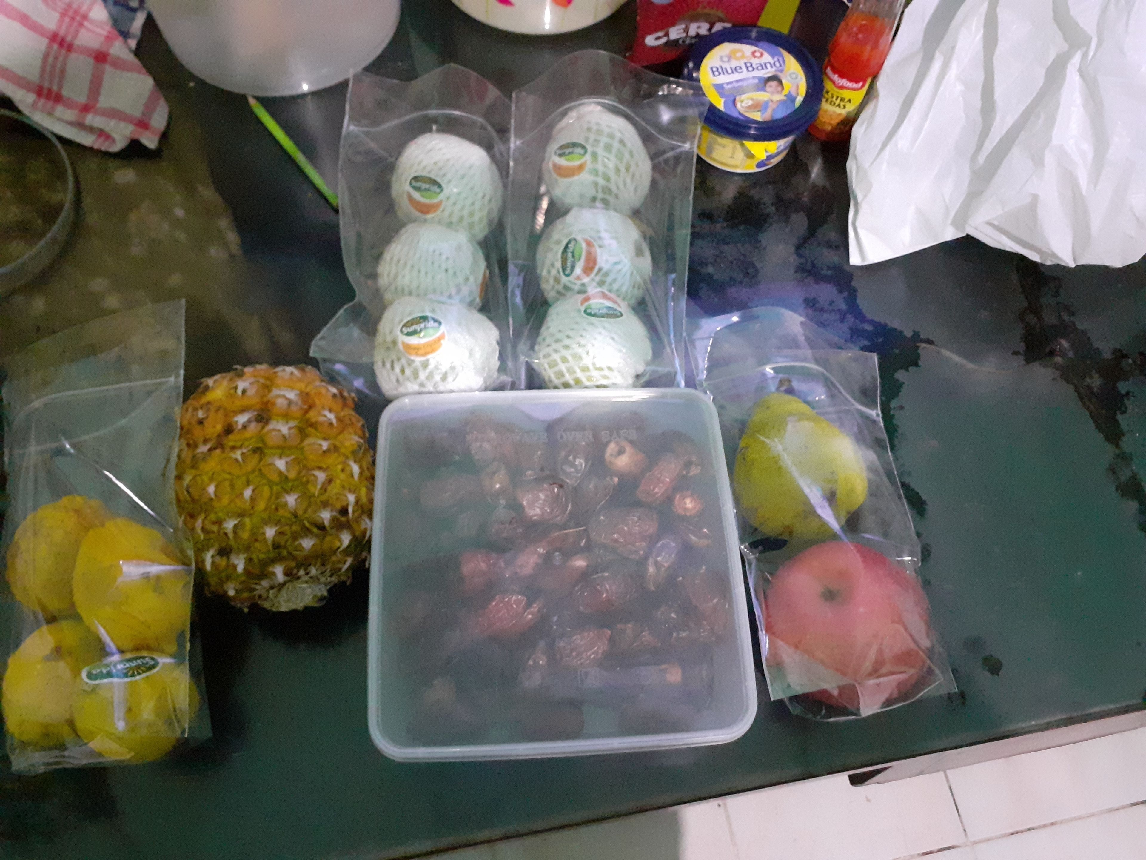 A kitchen counter with various packaged food items including fruits and a container of dried fruits.