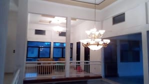 A spacious interior with a high ceiling, a chandelier, and a balcony with a railing. - Almira Homestay (Jambi)