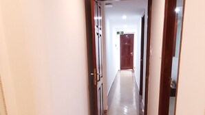Un pasillo estrecho con suelo de madera y paredes blancas.