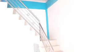 A staircase with metal railings and white steps, leading to a landing with a white door. - Almira Homestay near Airport - Hostel (Jambi)
