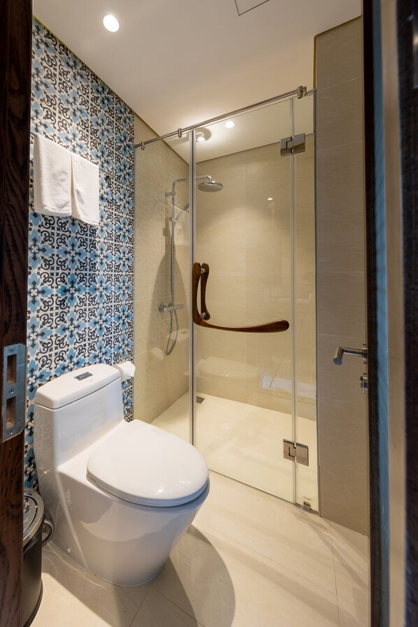 A modern bathroom with a glass-enclosed shower, a white toilet, and a patterned backsplash.