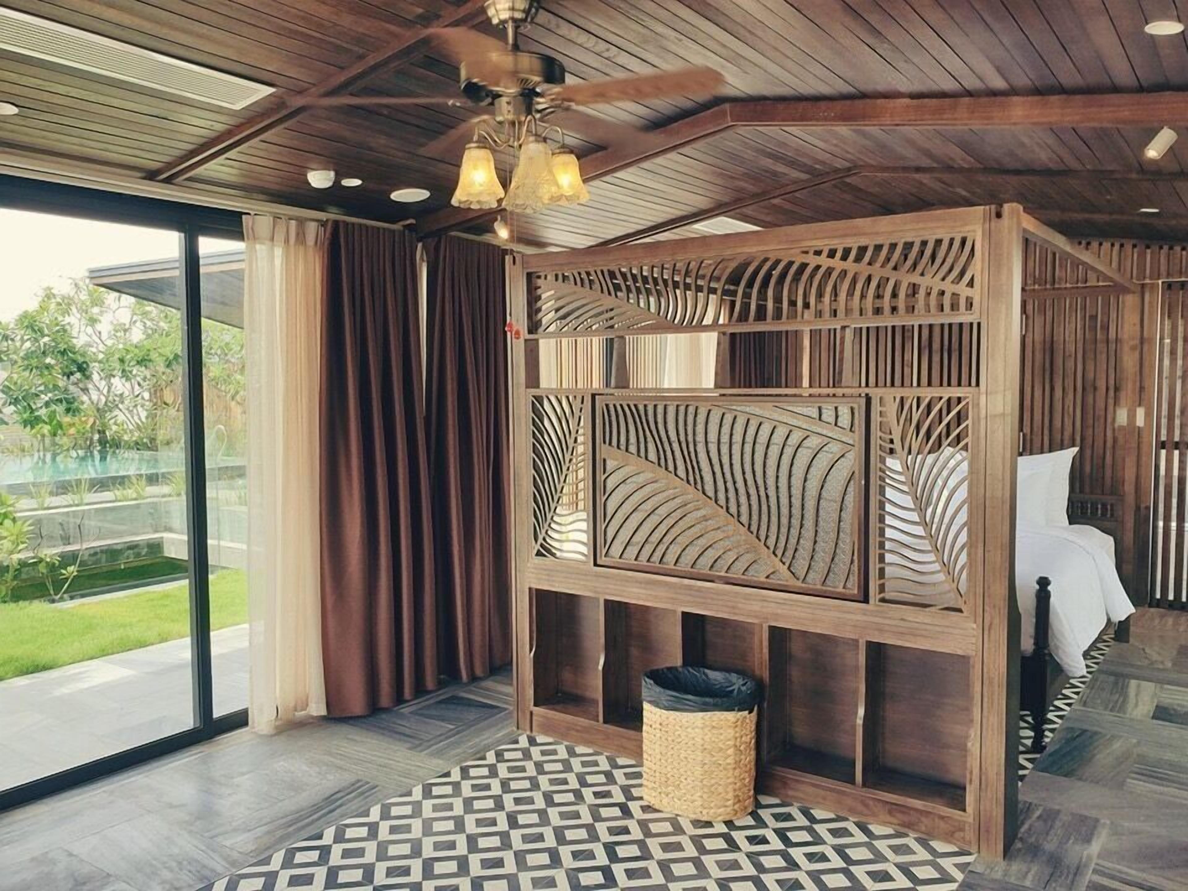 Una habitación con literas, ventilador de techo, ventana grande y suelo estampado.