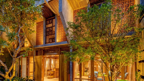 A multi-story building with traditional wooden lattice windows and balconies, surrounded by lush greenery and a well-maintained courtyard with seating areas. - Minh Boutique Hotel & Apartment (Da Nang)