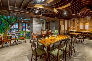 Een restaurant met houten meubels, een centrale tafel en uitzicht op een gebouw.