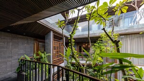 A modern interior with a glass ceiling, a wooden staircase, and lush greenery. - Minh Boutique Hotel & Apartment (Da Nang)