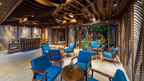 A modern interior with wooden ceiling beams, blue upholstered chairs, and a central round table. - Minh Boutique Hotel & Apartment (Da Nang)
