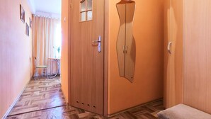 Ein Flur mit Holzboden, einer Tür inklusive Spiegel und einer Bank.