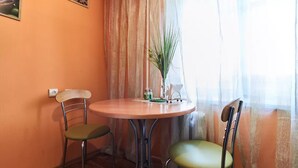 Ein kleiner runder Tisch mit zwei Stühlen, einer Topfpflanze und einer Vase mit Blumen.
