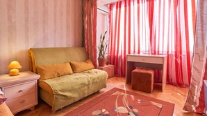 Ein Schlafzimmer mit Bett, Nachttisch, Lampe, Schreibtisch, Stuhl und Vorhängen.
