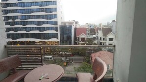 Un balcón con una mesa y dos sillas, con vista a un paisaje urbano con edificios modernos.