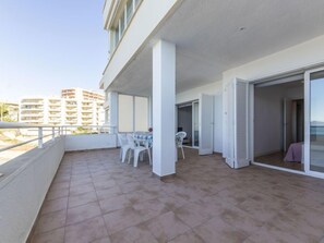 A balcony with a table and chairs, a sliding glass door, and a view of other buildings. - Apartment Rits by Interhome (Salou)