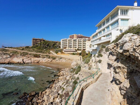 A coastal hotel with multiple floors, a rocky shoreline, and a clear view of the sea. - Apartment Rits by Interhome (Salou)