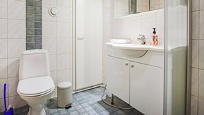 Kylpyhuone, jossa on wc, pesuallas, peili ja suihkutila.