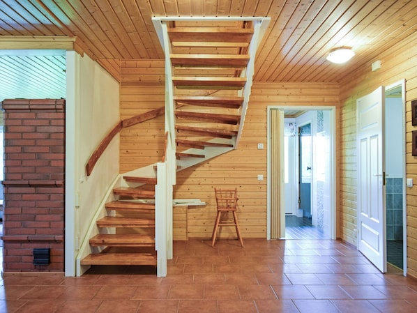 Una escalera de madera con un muro de ladrillo a un lado y una puerta que da a otra habitación.