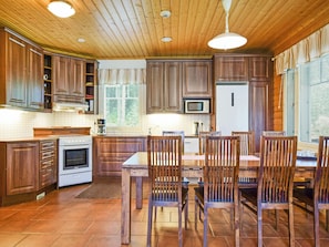 Una cocina con armarios de madera, una estufa blanca, un microondas y una mesa de comedor con sillas.