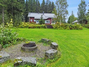 A house with a red exterior, surrounded by a well-maintained lawn and a fire pit area. - Arhippa by Interhome (Kuopio)