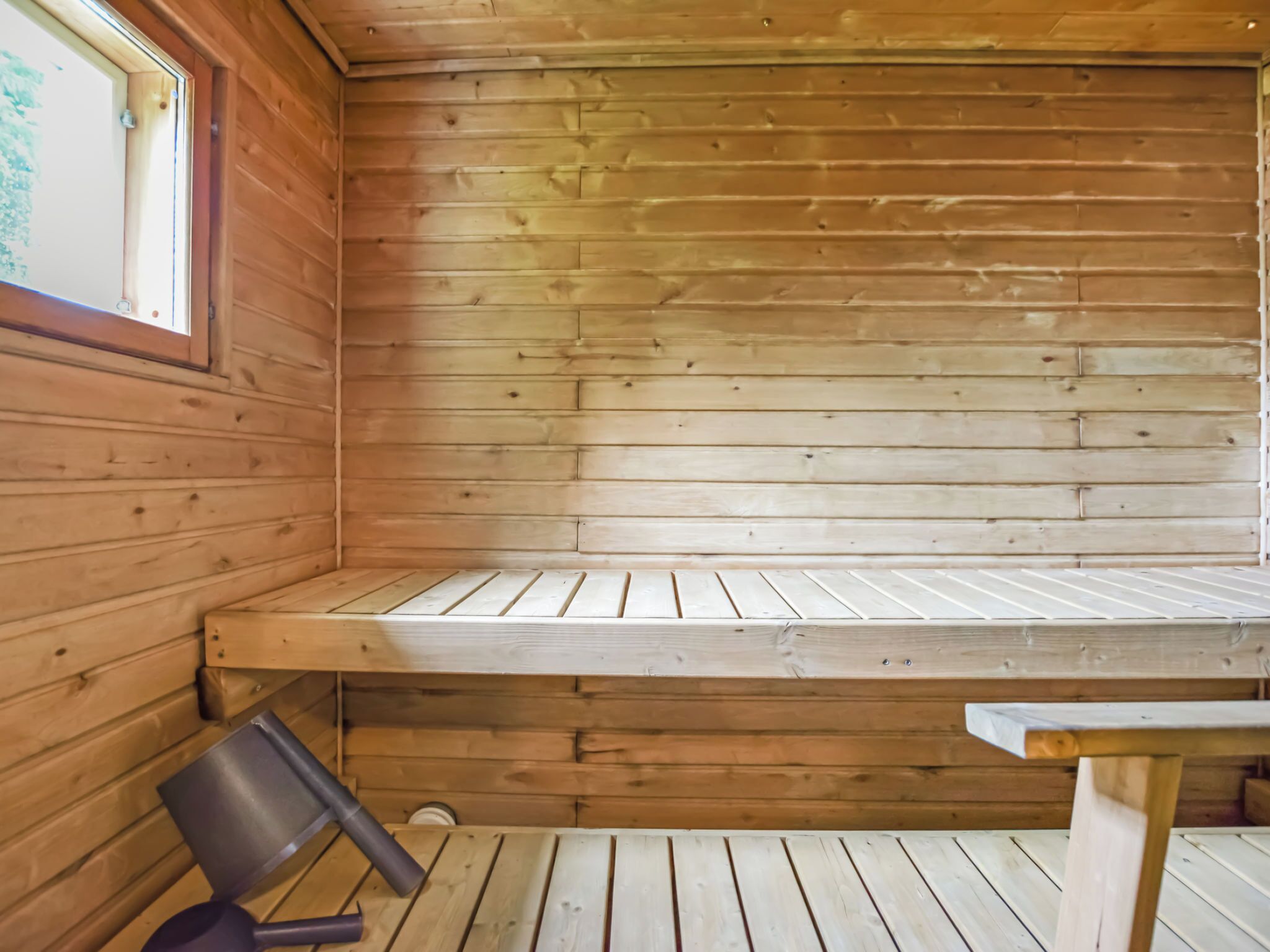 Een houten sauna met banken en een raam.