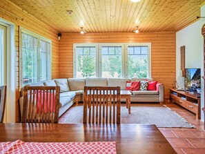 A cozy living room with a wooden ceiling, large windows, a sofa, a coffee table, and a TV stand. - Arhippa by Interhome (Kuopio)