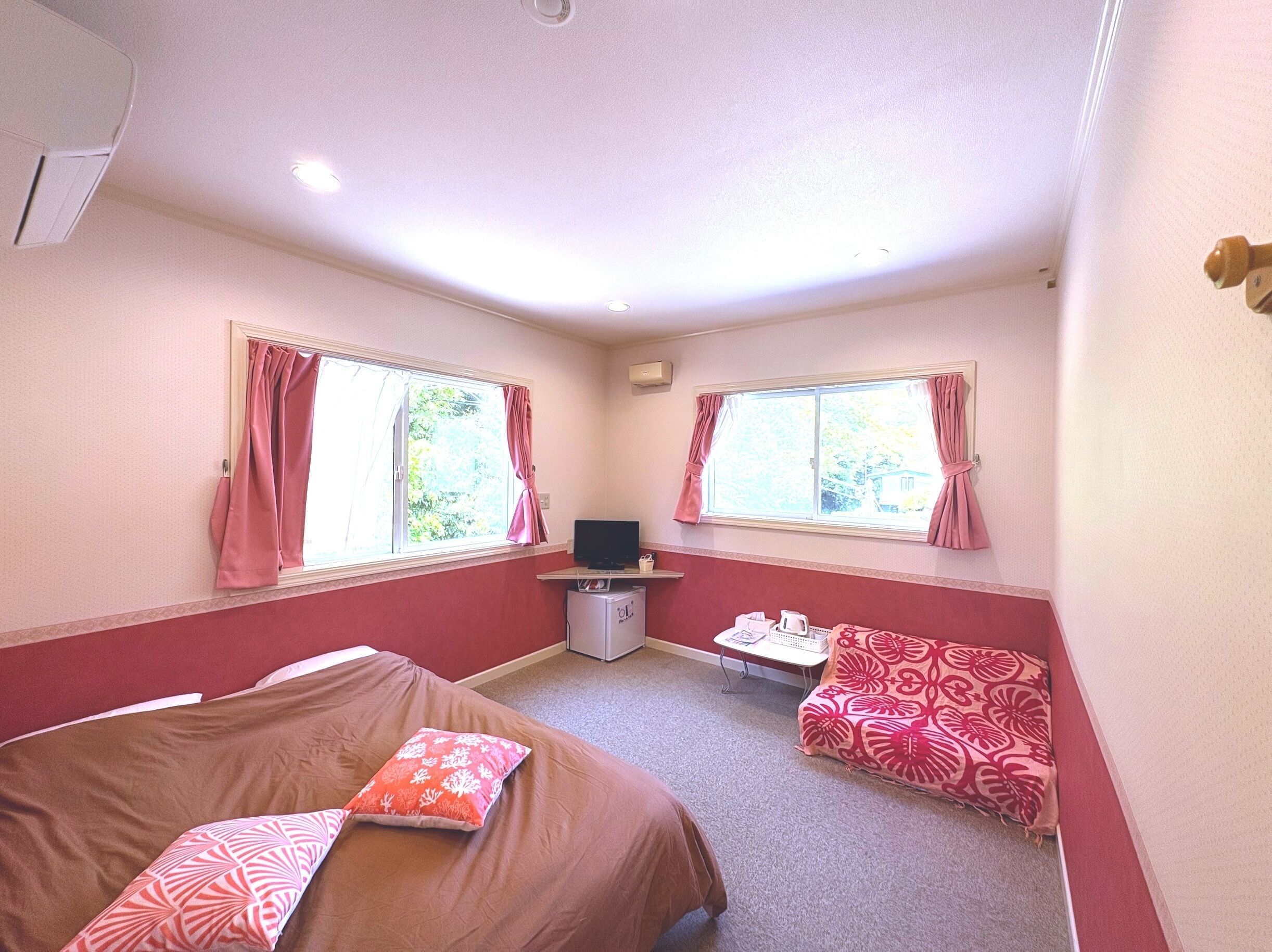 Een kamer met twee bedden, een bank, een televisie en een kleine tafel.