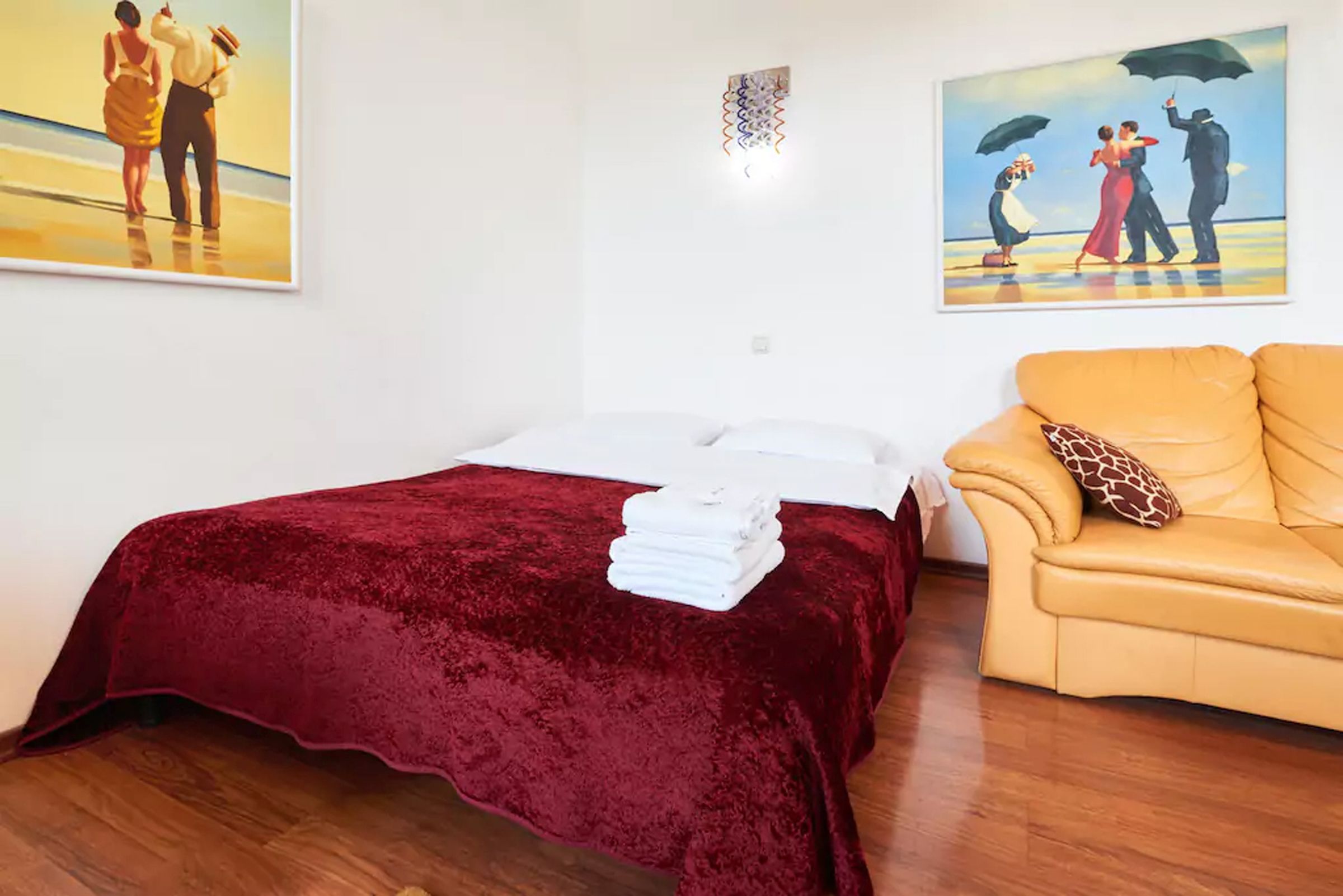 Una habitación de hotel con una cama, un sofá y dos cuadros en la pared.