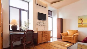 A living room with a desk, chair, sofa, and a TV mounted on the wall. - Home-Hotel Khoriva 15 (Kyiv)