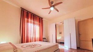Un dormitorio con cama, ventilador de techo, armario y espejo.