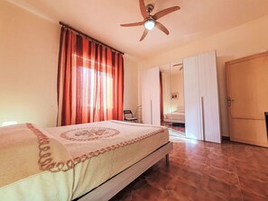 A bedroom with a bed, a ceiling fan, a wardrobe, and a mirror. - Giaquinta by Interhome (Marina di Modica)