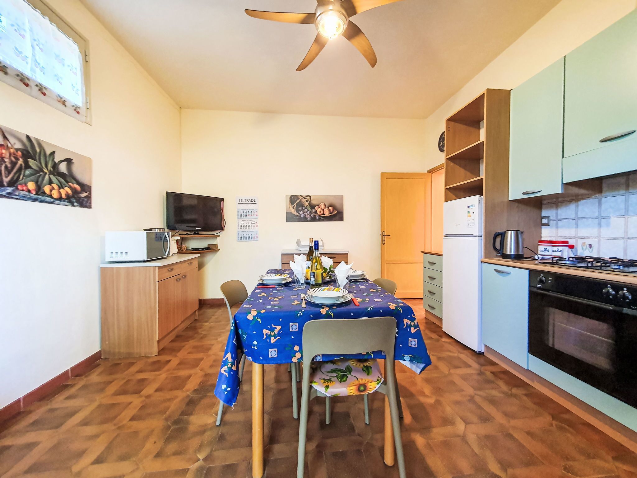 A compact kitchen with a dining table, chairs, a microwave, a stove, and a refrigerator.