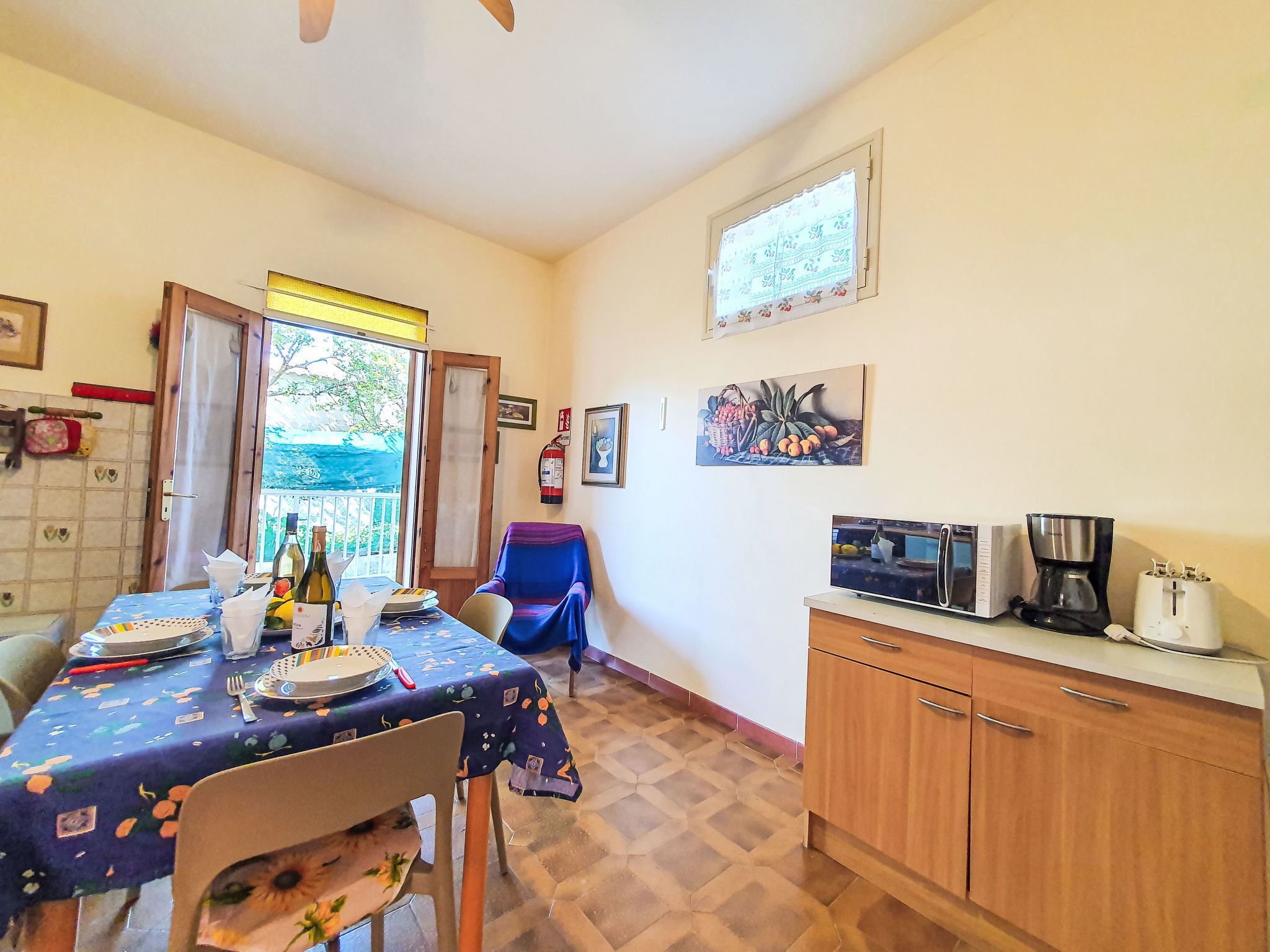 A kitchen with a dining table set, a chair, a cabinet, and a window with a view.