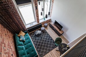 A modern living room with a green sofa, a black and white rug, and a brick wall. - Estonishing Stay (Tallinn)