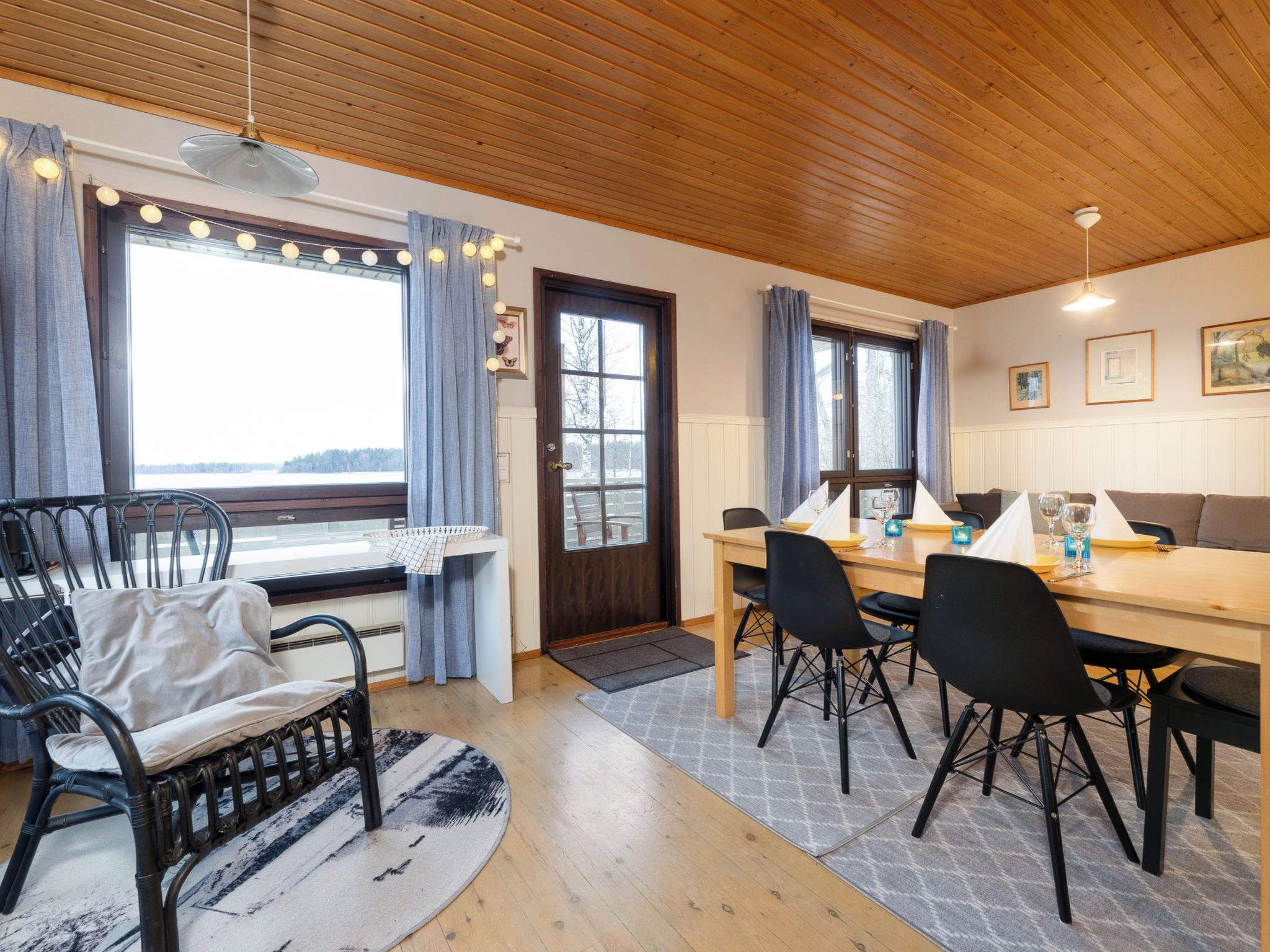 En mysig matplats med ett träbord, svarta stolar och utsikt över omgivningarna genom stora fönster.
